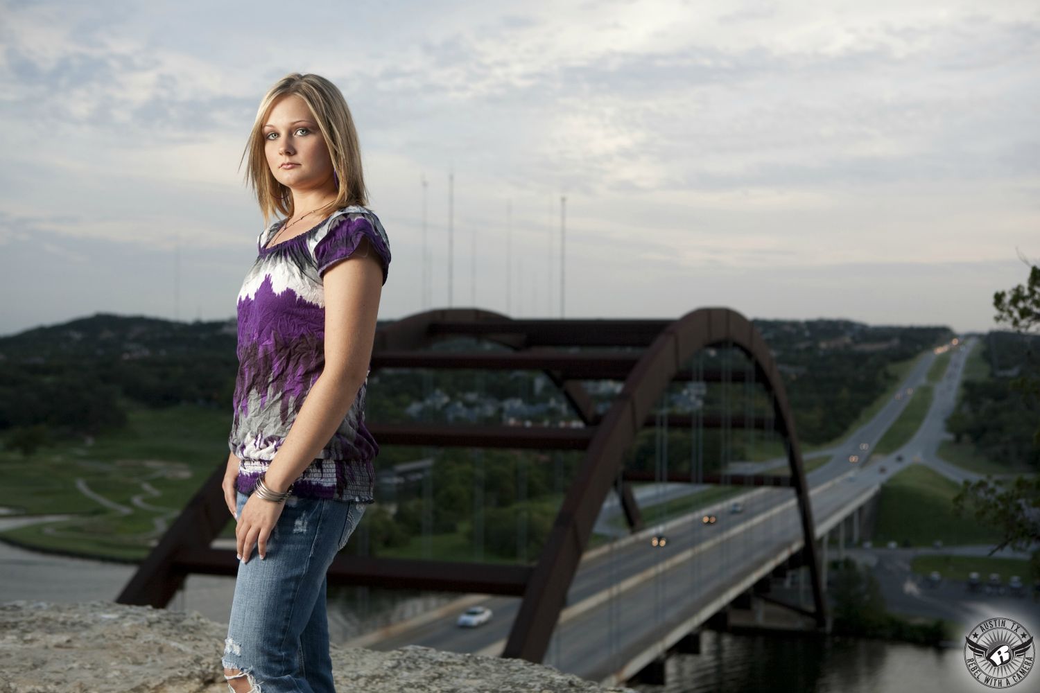 Picture of high school senior girl in colorful shirt and jeans at the Pennybacker Bridge taken by senior portrait photographer Austin.